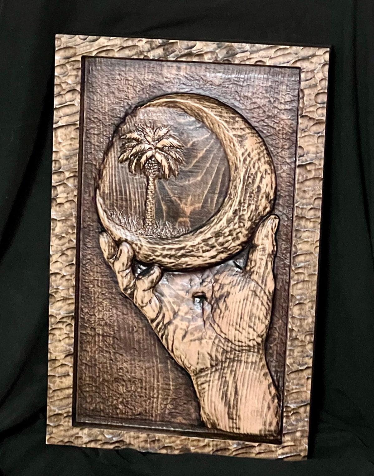 Custom 3D wood relief carving example — hands holding a coastal scene